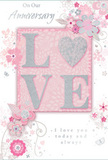 The photograph presents a tender anniversary card whose entire design radiates quiet romance, much like a peaceful evening stroll through Holborn's historic lanes. At the centre, the word LOVE is crafted in softly raised glitter, each letter outlined with delicate sparkle that suggests silvery candlelight. The O forms a gentle heart-shaped curve within the lettering, subtly emphasising the emotion without overpowering the refined style. This central word sits on a blush-pink panel, framed by a field of pastel tones-pale pinks, soft greys, and milky whites-that bathe the card in a calm, intimate glow. Surrounding the text, delicate blossoms unfold in muted blush and mauve, their petals painted with an almost watercolour softness. Slim, swirling stems and leafy tendrils weave between the flowers, adding motion and grace, like the flowing lines of a florist arranging an anniversary bouquet by hand. Tiny decorative touches-petal clusters, curling flourishes, and discreet butterfly silhouettes-dance along the edges, giving a sense of gentle movement, as if a light spring breeze had skimmed across the paper. In refined script, the phrases On Our Anniversary and I love you today and always appear, the lettering elegant yet warm, spaced thoughtfully so it is easy to read without crowding the design. The overall impression is of a keepsake meant to be treasured: soft as a whispered promise, yet deeply heartfelt, like receiving a bouquet in a Holborn flat and pausing for a moment to remember how far a shared journey of love has come.